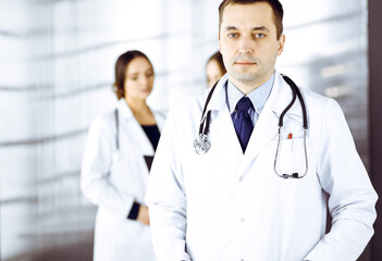 Fototapeta premium Professional middle aged doctor with a stethoscope at work with colleagues in a clinic. Perfect medical service in a hospital. Medicine and healthcare concept