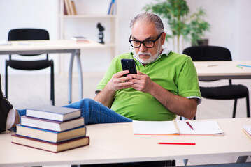 Old male student preparing for exams in the classroom