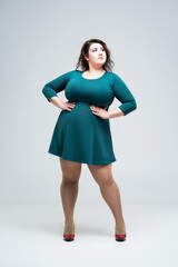 Sexy plus size fashion model in green dress, fat woman on gray background, body positive concept