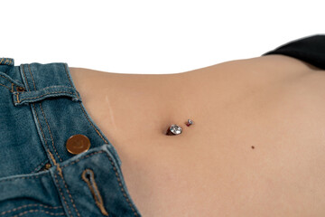 Belly button or navel piercing, of young woman wearing jeans isolated on white.