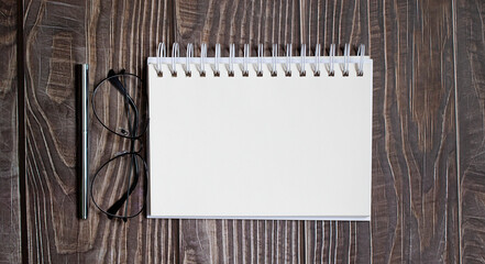 blank notebook with pen,glasses on wooden table, business concept