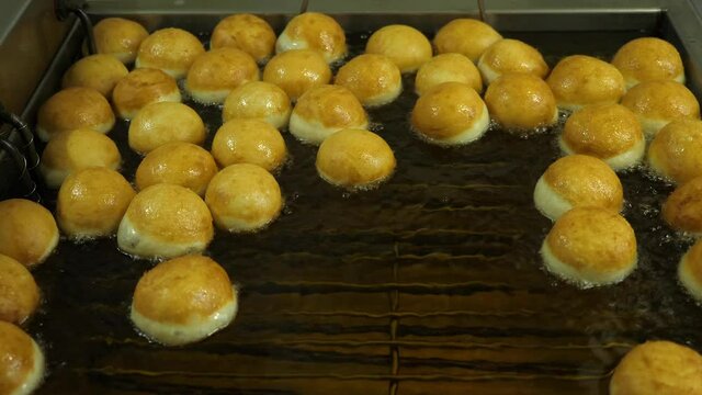 Sufganiyah Doughnut rolls for Jewish holiday of Hanukkah in deep fry.