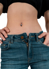 Belly button or navel piercing, of young woman wearing jeans isolated on white.