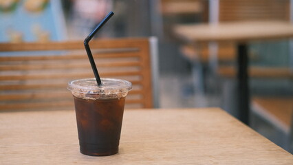 ice coffee with a plastic straw on the outdoor table at a cafe