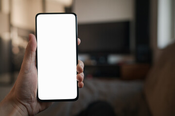 POV photo of man holding smartphone with white screen while sitting on a couch