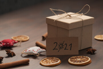 Christmas gift box from eco friendly paper wrapped with natural twine on wood table with natural decorations and 2021 card