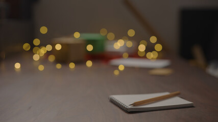 Notepad with pencil on walnut wood table with christmas lights on background
