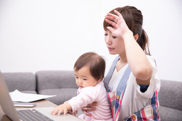 パソコンを使う主婦と赤ちゃん  © buritora