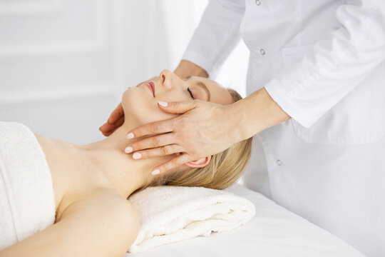 Beautiful caucasian woman enjoying facial massage with closed eyes in spa salon. Relaxing treatment in medicine and Beauty concept