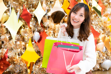 Young woman shopping many presents for her family during Christmas season in the paper bags with smile and happiness face from shopping mall, prepare the gifts, everyone,in Christmas Eve and New Year 