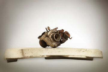 Rusty and carbonized old turbocharger on concrete weight from washing machine