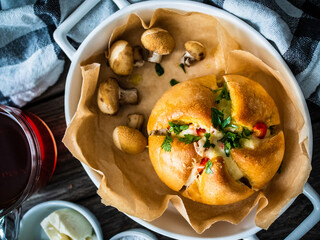 Breakfast - baked stuffed bun with mozzarella ham and red pepper vegetables on wooden table
