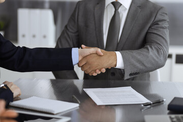 Unknown business people are shaking hands after contract signing in modern office, close-up. Handshake as successful negotiation ending