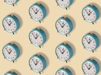 Pattern made with blue old alarm clock on yellow background