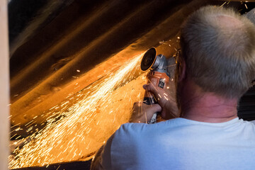 A person cutting metal roof with a flex with sparks flying