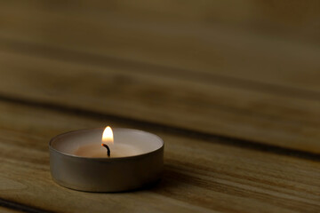Obraz na płótnie Canvas Burning lonely candle with on wood background, shot with shallow depth of field