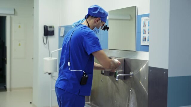 Doctor washes his hands with soap and running water. Correct way to wash hands according to the World Health Organization. Male surgeon disinfects hands before surgery.