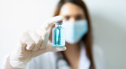 Doctor on laboratory holding liquid vaccines in glass bottle, concept of corona virus vaccine