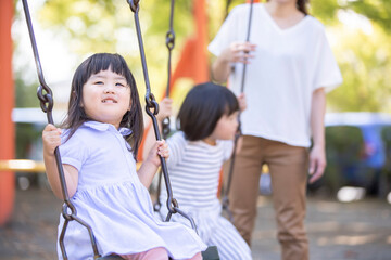 ママとブランコで遊ぶ子供
