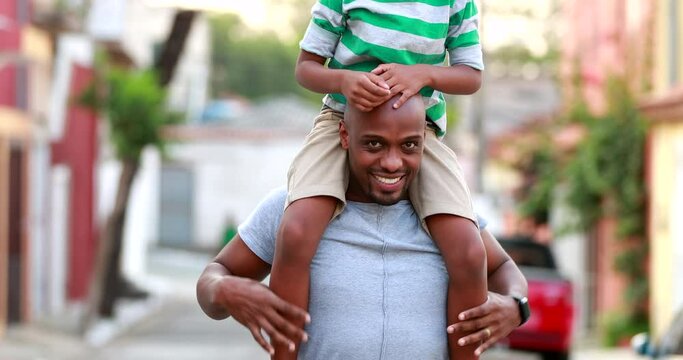 Father lifting son to shoulders, African child and dad bonding