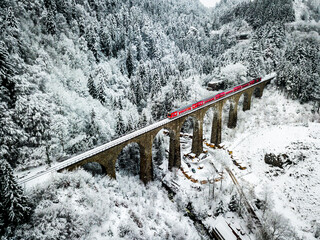 Local train crossing the snowy Ravennaschlucht bridge