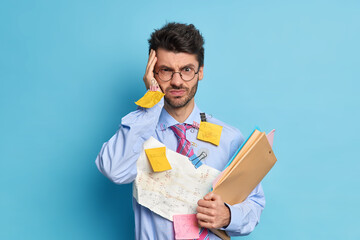 Intensed serious unshaven male student has headache because of long work busy preparing for math...