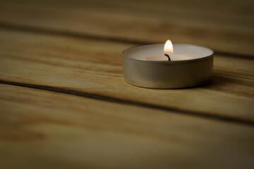Obraz na płótnie Canvas Burning lonely candle with on wood background, shot with shallow depth of field