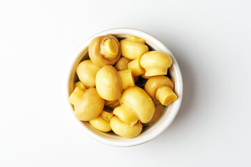 Canned mushrooms in a bowl on a white background. Top view.