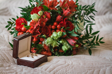 Wedding bouquet for the bride of red flowers and wedding rings in a red box