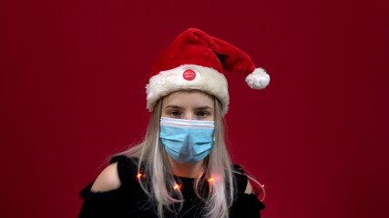 Fototapeta na wymiar Woman in medical mask singing and dancing along with a dancing christmas live hat on her head