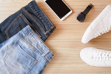 Top view or flat lay of Dark blue and faded blue jean , mobile phone , smart watch and white...