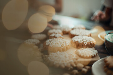 Mom and children decorate Christmas gingerbread at home. A boy and a girl paint with cornets with...