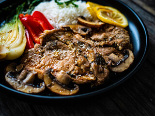 Fried pork steaks with lemon, basmati rice and steamed pak choi cabbage served on wooden table
