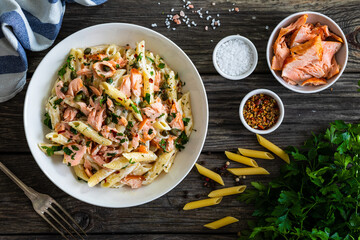 Penne with roasted salmon nuggets on wooden table
