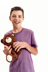 Portrait of happy teenaged disabled boy with cerebral palsy smiling at camera and holding his teddy...