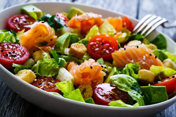 Salmon salad - smoked salmon with avocado and mix of  vegetables on wooden table