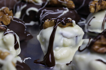 Close up of homemade black and white christmas chocolate pralines filled with walnuts, marzipan and...