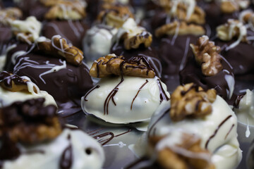 Close up of homemade black and white christmas chocolate pralines filled with walnuts, marzipan and figs