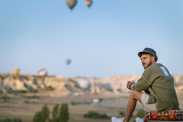 Young tourist man watching a hot air balloon tour in Cappadocia. - Powered by Adobe