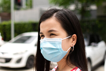 Young Asian woman wearing medical hygiene protective face mask in parking lot.
