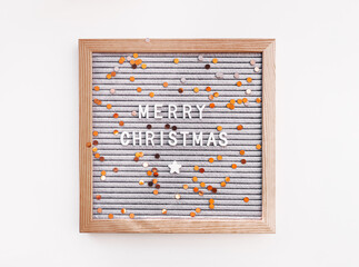 Letter board with Merry Christmas greeting and scattering golden confetti. New Year celebration. Copy space on white background.
