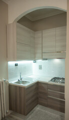 View of a modular corner kitchen in gray and brown color, the led under-cabinet light attracts attention.