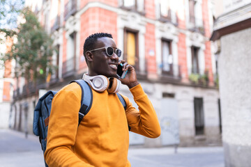 Black Man Having Phone Call Wearing Yellow Sweater Outdoors.