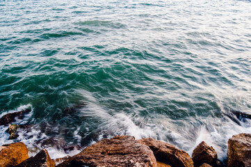 sea green waves crash against stones. The coast