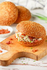 Delicious sesame bun sandwich with chicken salad, fried bacon, green onions, cheese with ranch sauce. Lunch or dinner for gourmets. Selective focus