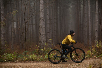 Young man taking a brake during biking through autumn forest