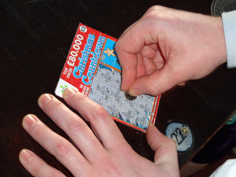 London, UK, April 11, 2010 : Scratching A Christmas Scratchcard Lottery Ticket Gambling To Win A Prize During The Festive Season, Stock Photo Image