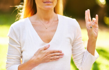 Beautiful mature woman meditating in green sunny garden, healthy lifestyle