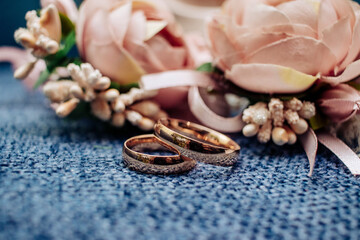 Fototapeta na wymiar wedding rings with flowers on a blue textured background