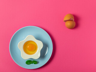 egg yolk and white in a bowl and plate on a solid color background background